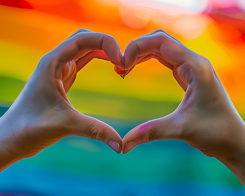 Hands making a heart shape in front of a rainbow; LGBTQIA+ therapist in Madison, WI