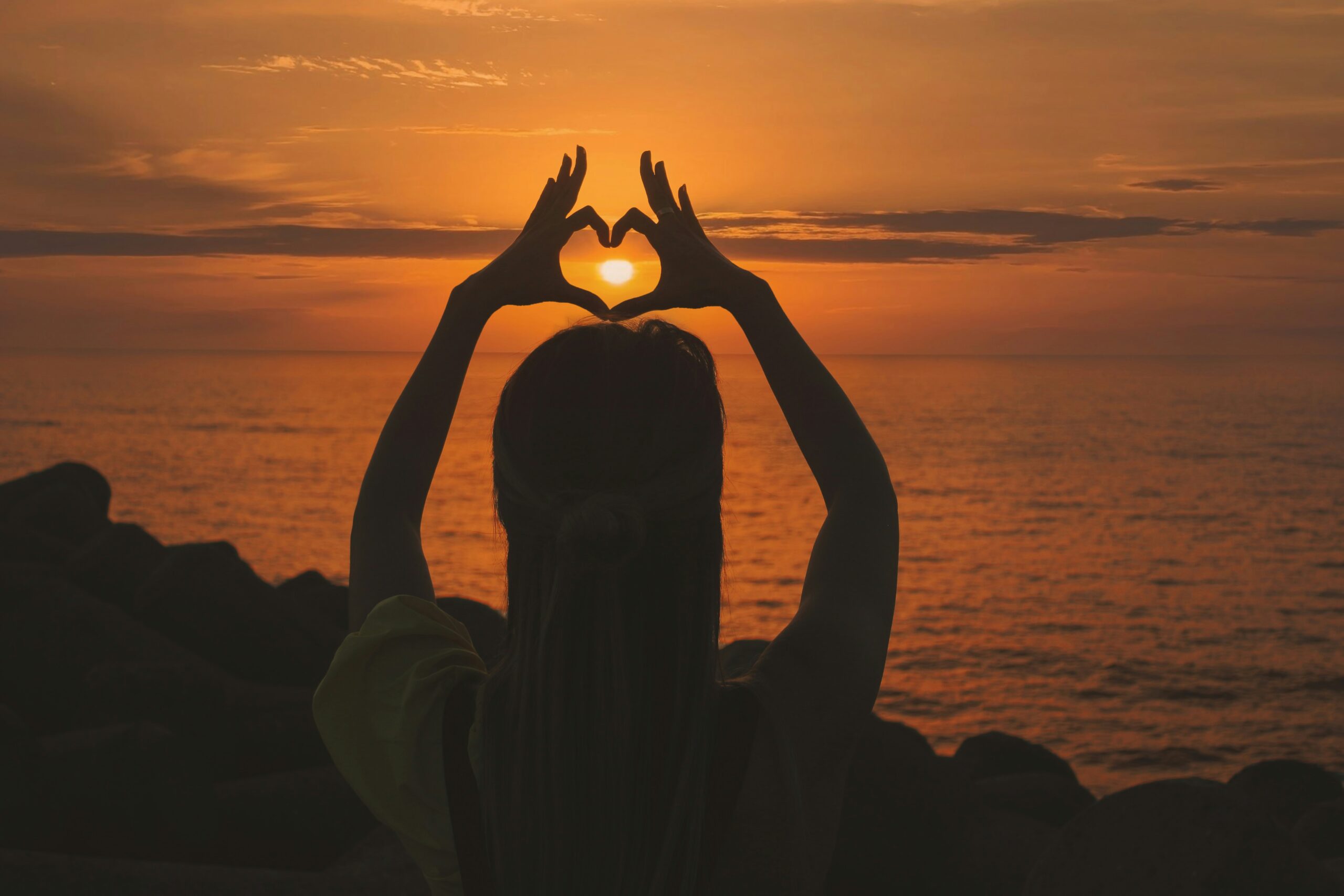hands making a heart at sunset