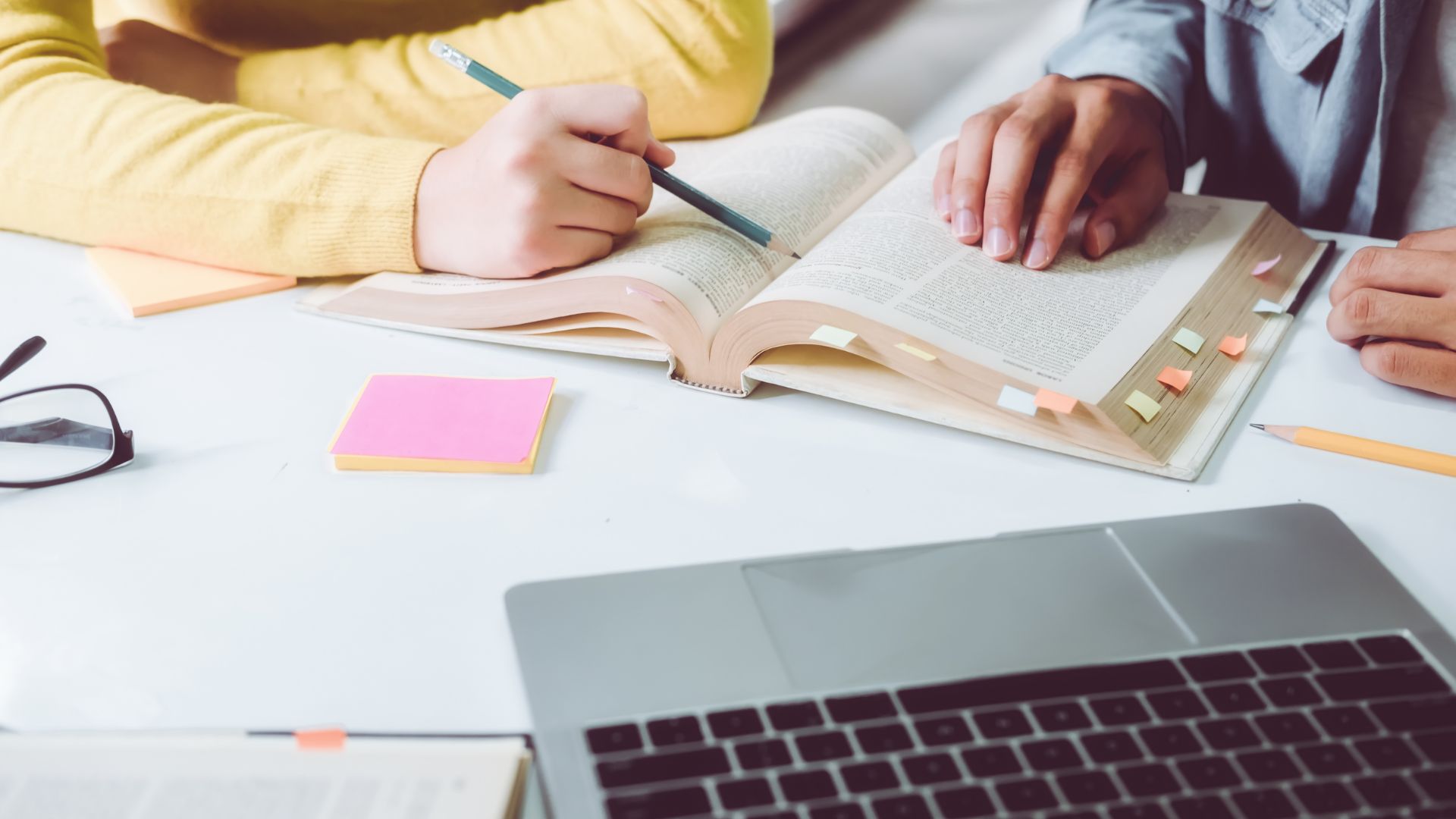 Two teens reading a book and doing homework together — back to school mental health tips
