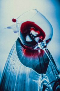 Spilled glass of red wine with heart shapes reflecting in liquid representing emotional impact of alcohol use for alcohol awareness month Wisconsin