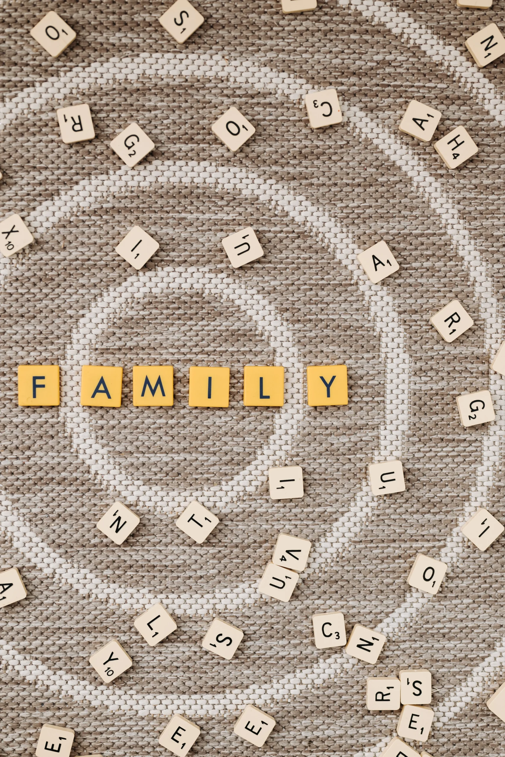 The word "family" spelled with letter tiles, representing family relationships, intergenerational patterns, and genogram therapy used in trauma-informed counseling.