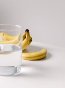 Glass of water and bananas representing hydration and nourishment as basic forms of everyday self-care.